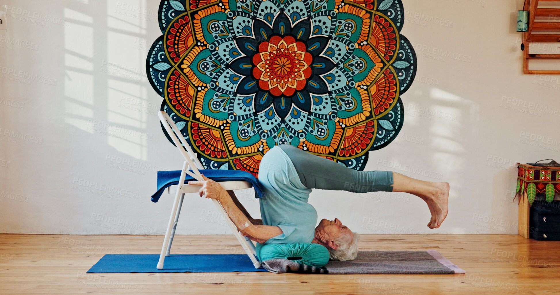 Buy stock photo Chair, upside down or yoga and woman in studio with wall art for fitness or wellness routine. Balance, exercise or pilates and senior person in class with mandala symbol for holistic spine health