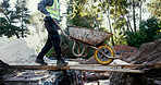 Person, wheelbarrow and materials at construction site outdoor, cement and concrete mixing. Male contractor, builder and transport tools for gravel, soil and renovation items at industrial excavation