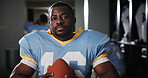 Man, American football player and ball in portrait in locker room, strong and ready for sports contest. Person, athlete and equipment with confidence, career and serious for competition at club