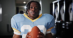 Black man, American football player and ball in portrait in locker room, strong and ready for sports contest. Person, athlete and equipment with confidence, career and club for competition in USA
