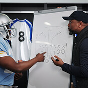 Board, writing and football with coach and team in locker room for game ...