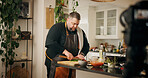 Vegetables, cooking and man with live streaming in kitchen for dinner tutorial, meal prep and cutting ingredients. Culinary influencer, person and cuisine vlog for content creation and online guide