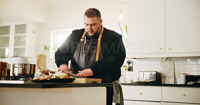 Buy stock photo Man, chef and cutting in kitchen with food for meal prep, dinner or private catering service at home. Male person, culinary artist or chopping board with stove for hospitality, recipe or ingredients