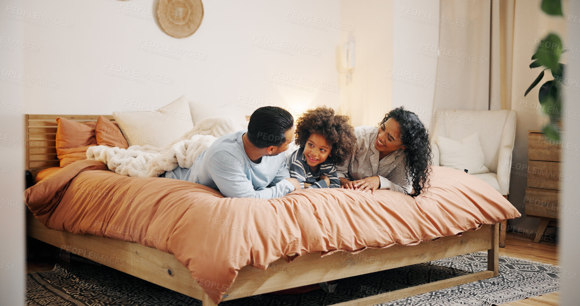 Buy stock photo Bedroom, parents and bonding with child, smile and talking to boy in home, relax and family with love. Morning, man and woman with kid in house, mom and dad with care for son, conversation or happy