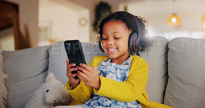 Buy stock photo Phone, headphones and happy child in home for online learning, music and play game for education. Girl, audio and kid with mobile in living room for internet app, streaming cartoon and watch video