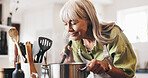 Aroma, cooking and mature woman in kitchen in home with smelling dinner, meal or dish. Happy, pot and female person with satisfaction for scent of supper with health, wellness and nutrition in house.