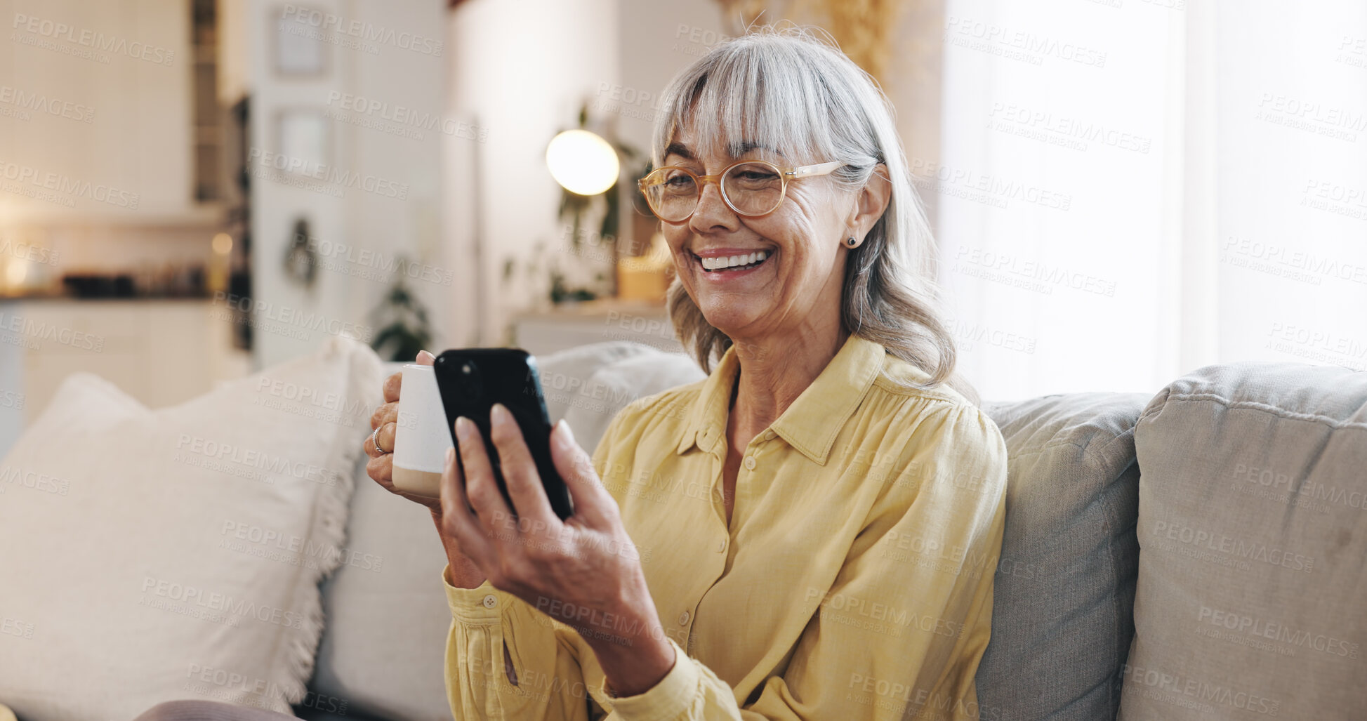 Buy stock photo Coffee, phone and smile of senior woman on sofa in living room of home for break or retirement. App, meme and social media with happy mature person drinking caffeine beverage in apartment to relax