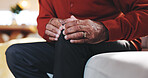 Accident, hands and knee pain with mature person on sofa in living room of home for arthritis. Emergency, injury or joint inflammation and senior in apartment with osteoarthritis or tendinitis