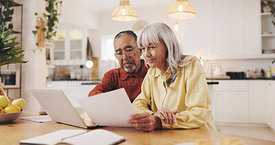Buy stock photo Senior couple, documents and finance in home for results, laptop or smile with review for pension. Interracial relationship, man and woman for budget, happy or profit for retirement income in kitchen