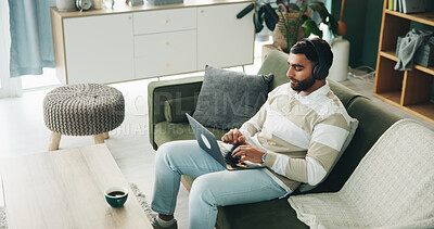 Buy stock photo Headphones, man and laptop in home for hybrid work, journalism and research story. Typing, music and freelancer on sofa with computer for streaming audio, writing article and news report on internet