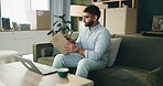 Box, label and man with laptop on sofa for delivery for online shopping, ecommerce and shipping. Happy, living room and person with parcel on computer for checklist, digital receipt and invoice