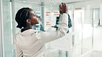 Black woman, writing or brainstorming with glass board for schedule planning at office. Female person, planner or employee taking notes with mindmap ideas for strategy, reminder or tasks at workplace