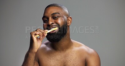 Buy stock photo Toothbrush, smile and black man in studio for hygiene, fresh breath and mockup in morning. Portrait, wellness and person brushing teeth for dental care, cleaning or grooming on grey background space
