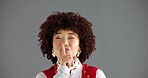 Wink, secret and woman with finger on lips for silence, private or confidential news on gray background. Gossip, whisper or shush in portrait, rumor or studio space with communication for quiet