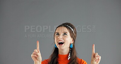 Buy stock photo Happy woman, pointing up and info in studio for advertising, announcement or news about us on gray background. Mockup space, presentation or coming soon with gesture, sign or direction for launch