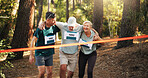 Race, people running and help to finish line for exercise aid, fitness and challenge together in forest. Mature team, runner and support for marathon with leg injury, sprain or tired at sports event
