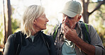 Senior couple, hiking and talking for route direction and tourism on holiday with travel decision. People, retirement and hikers in discussion for planning, trekking or outdoor adventure in woods