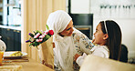 Muslim, mother and child with flowers in home for mothers day surprise, birthday dinner and gratitude. Happy family, love and woman with bouquet gift at dining table for celebration and special event