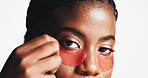 Black woman, portrait and eye patches with cosmetics for collagen or hydration on a white studio background. Face, female person or model with facial gel mask for dermatology or anti aging treatment