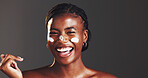 Happy, black woman and portrait with lotion in studio for skincare on a gray background. Face, female person or model with smile in satisfaction for moisturizer, cream or facial treatment on space