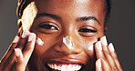 Happy, black woman and portrait with face cream in studio for skincare on a gray background. Closeup, female person or model with smile in satisfaction for lotion, moisturizer or facial treatment