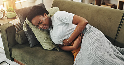 Buy stock photo Black woman, pain and stomach cramps on sofa for virus, digestion problem and endometriosis. Person, discomfort and hold tummy in home for menstrual period, constipation and gastro for acid reflux