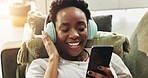 Headphones, black woman and relax with phone on sofa for wellness podcast, stress relief and music playlist. Home, person and smartphone with eyes closed for calm sound, zen audio and weekend break