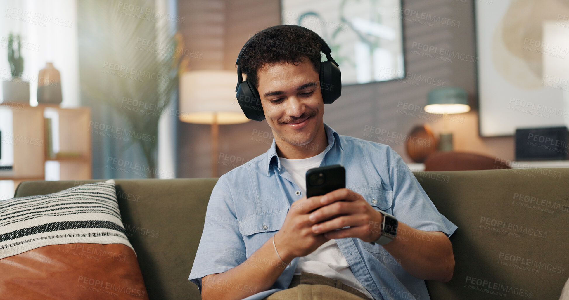 Buy stock photo Headphones, man and happy with phone on sofa for social media video, streaming service and weekend break. Relax, person and smartphone in home for sound playlist, music album and audio subscription