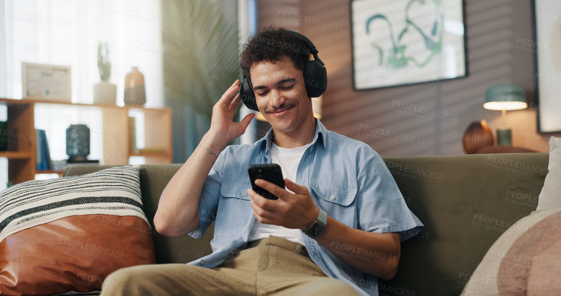 Buy stock photo Happy man, sofa and headphones with music for audio streaming, podcast or entertainment at home. Male person, relax or user with smile on mobile smartphone for sound, playlist or songs at house