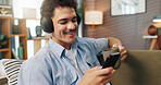 Headphones, man and relax with phone on sofa for streaming service, watching online video and coffee break. Happy, person and smartphone in home for audio playlist, music album or internet connection
