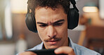 Online, video games and man with headphones, smartphone and serious for virtual sport in apartment. Streaming, gamer and person with mobile app for entertainment, playing or player with tech in house