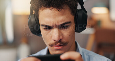 Buy stock photo Online, video games and man with headphones, smartphone and serious for virtual sport in apartment. Streaming, gamer and person with mobile app for entertainment, playing or player with tech in house