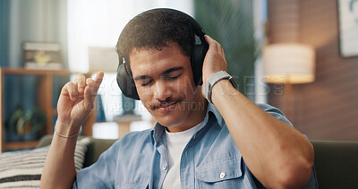 Buy stock photo Dance, music and man with headphones in home for streaming service, hip hop playlist or podcast. Technology, sofa and person listening to song, album and finger snap for audio on weekend to relax