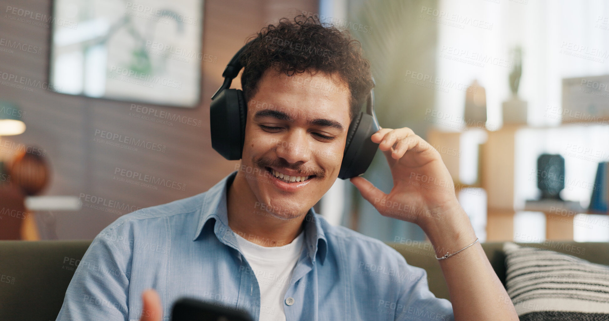 Buy stock photo Headphones, man and happy with phone in home for streaming service, feel good playlist and audio subscription. Relax, person and internet connection on sofa for watching online video and social media