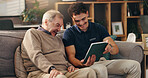 Old man, nurse and tablet on sofa, happy and help for streaming movie in lounge at apartment. Caregiver, elderly person and digital touchscreen for film, app and relax with laugh in retirement home