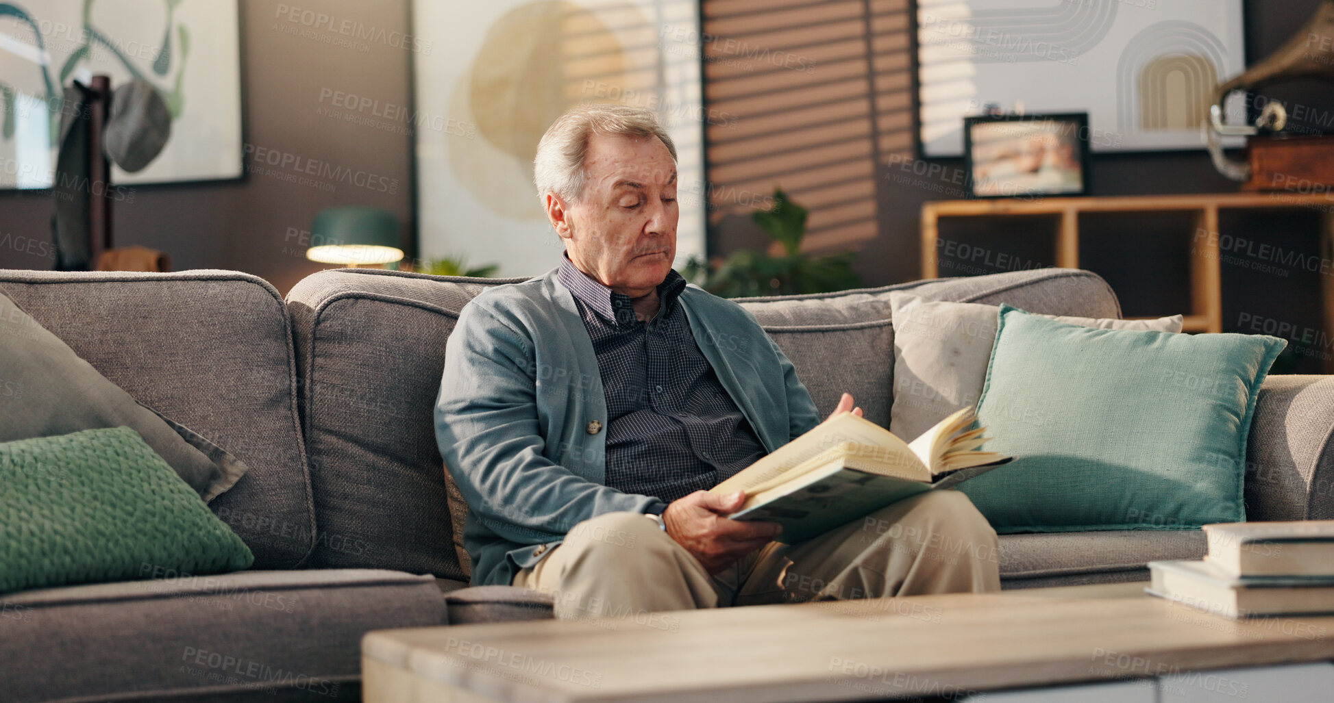 Buy stock photo Senior man, reading book and relax on sofa with study, literature and information in lounge at apartment. Elderly person, novel and knowledge on couch with language for storytelling in living room