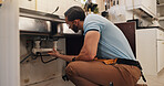 Man, plumber and inspection in kitchen, pipe and sink with search for leak, problem solving and repair in home. Person, handyman and check for water, drain and solution for maintenance at apartment