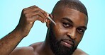 Portrait, serum and black man in studio, skincare and dermatology on blue background. African person, facial cosmetics or model with dropper, hyaluronic acid and oil with collagen, glow or anti aging