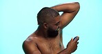 Black man, spray or deodorant for armpit with hygiene in studio, fragrance or grooming with cosmetic product. Underarm smell, perfume or spritz for scent, male person and self care on blue background