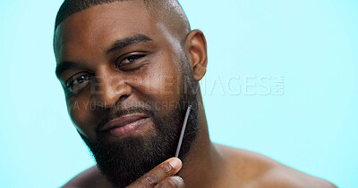Buy stock photo Face, black man and beard with comb for styling, beauty with haircare and cosmetics on blue background. Facial hair, self care and healthy glow with brushing on studio, dermatology and grooming