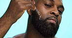 Portrait, serum and black man in studio, beauty and dermatology on blue background. African person, facial cosmetics or model with dropper, hyaluronic acid and essential oil with shine or skincare