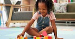 Black girl, block and building with toys for playing or fun activity on floor at elementary school. Kid, child or student with shapes for playful learning, fine motor skills or education in classroom