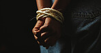Black background, studio and hands of person with rope for prisoner, hostage and victim. Bondage, mockup space and closeup for human trafficking, domestic violence and crime for slavery or trauma