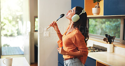 Buy stock photo Woman, music and singing with headphones in kitchen for audio playlist, weekend entertainment and radio sound. Fun, person and karaoke with spoon in home for online song, listening to album and relax