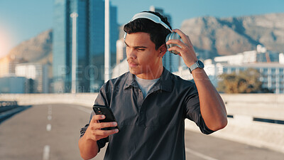 Buy stock photo City, phone and music with runner man outdoor for break from cardio or fitness routine. Exercise, headphones and streaming with confident athlete in urban town for running, sports or workout playlist