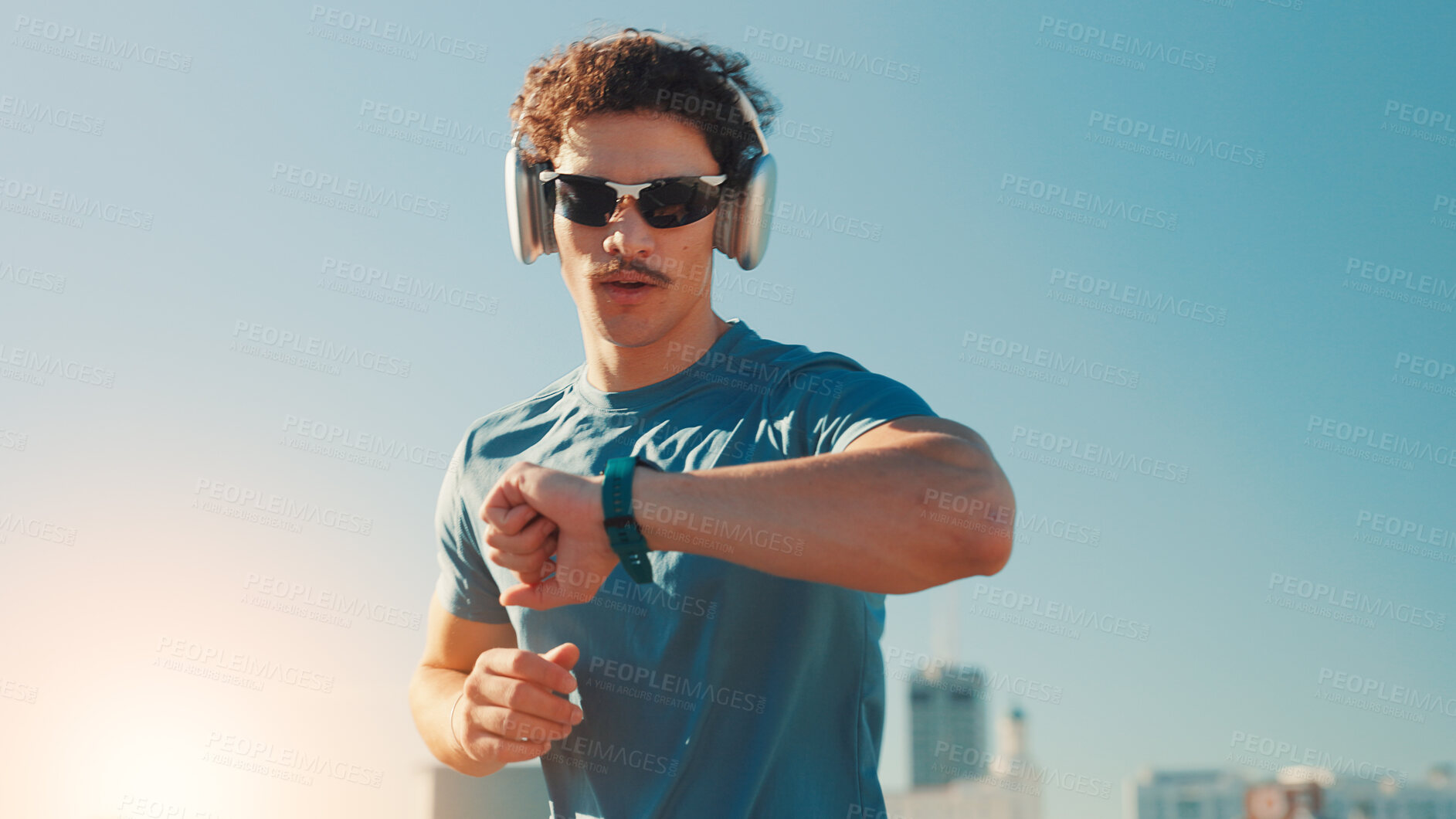 Buy stock photo Man, fitness and checking watch with headphones in city for workout app or tracking performance. Active, male person or runner with wristwatch for music, calories or running exercise on space in town
