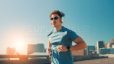 Buy stock photo Man, fitness and running with headphones in city for workout, cardio exercise or outdoor training. Active, male person or runner with sunglasses, music or road for physical activity in an urban town