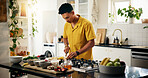 Cooking, concentration and cutting with man in kitchen of home for hobby, meal prep or nutrition. Ingredients, passion and recipe with person in apartment for diet, health or supper as culinary chef