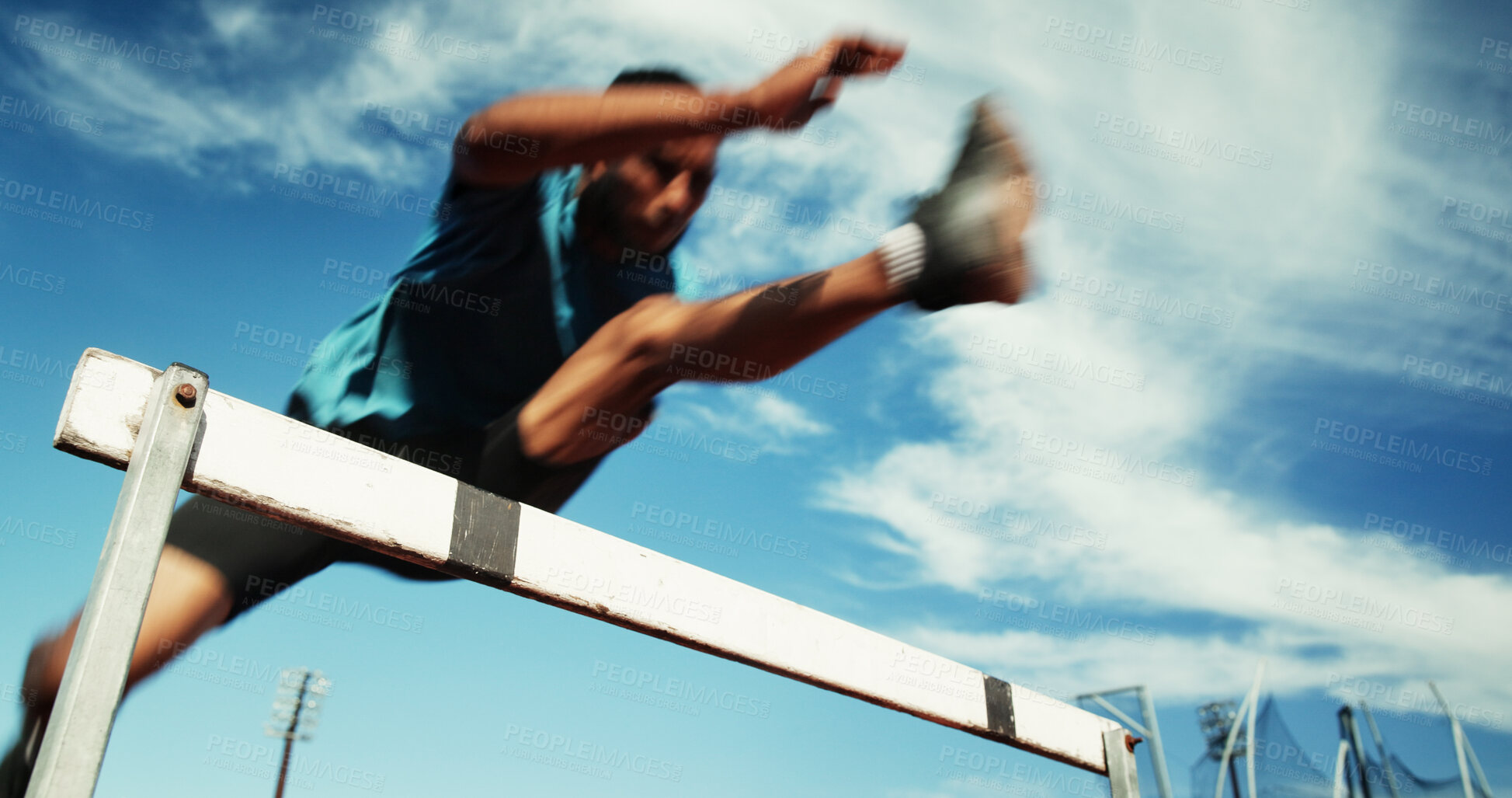 Buy stock photo Man, athlete and jump by hurdle for fitness competition, challenge and contest at sports field. Low angle, sprint obstacle and sky with blur for speed, leap and performance for marathon event