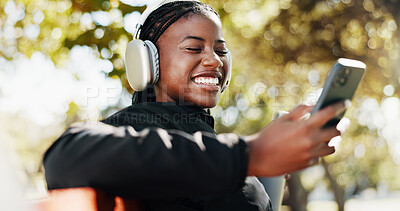 Buy stock photo Outdoor, athlete and woman with smartphone, headphones and tracking progress of exercise on app and smile. Happy, browsing and black person with mobile for social media, online and listening to music